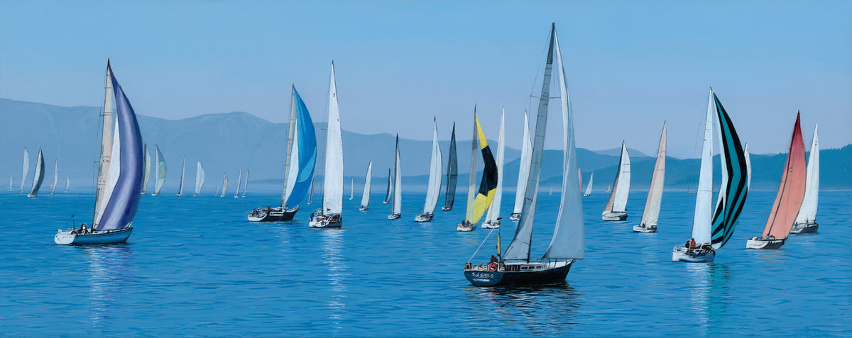 Sailing boats with colorful sails on a calm blue sea with mountains in the background